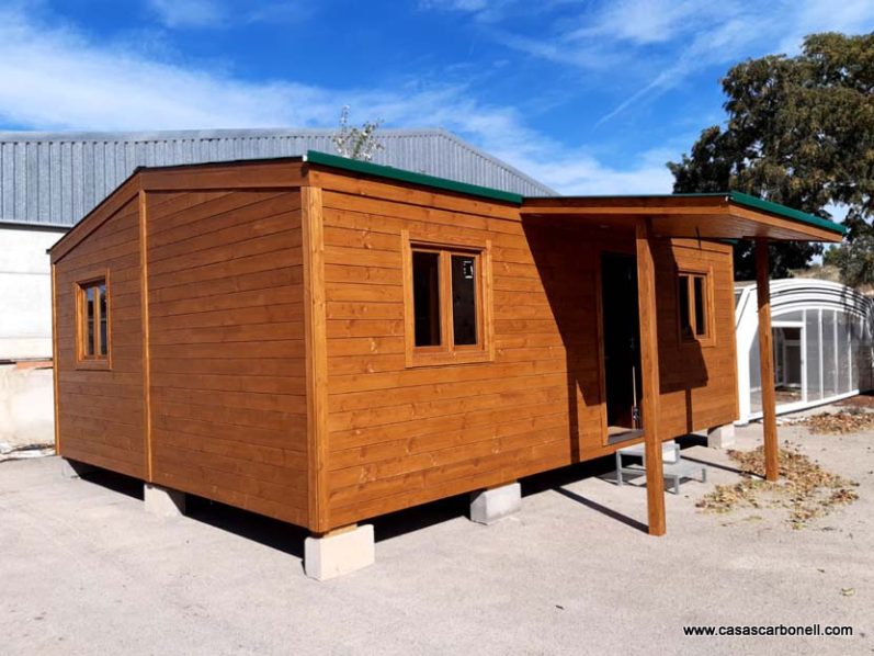 Casa de madera de un solo piso con ventanas y porche en un entorno exterior.