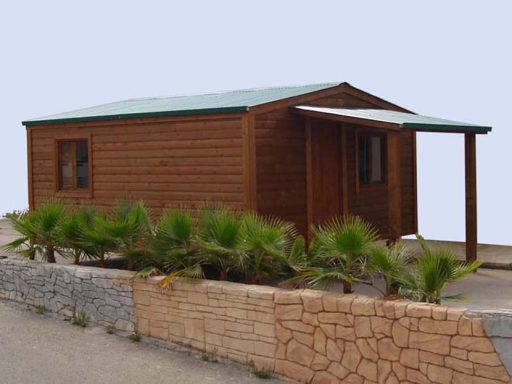 Casa de madera con techo a dos aguas y porche frontal, rodeada de vegetación.